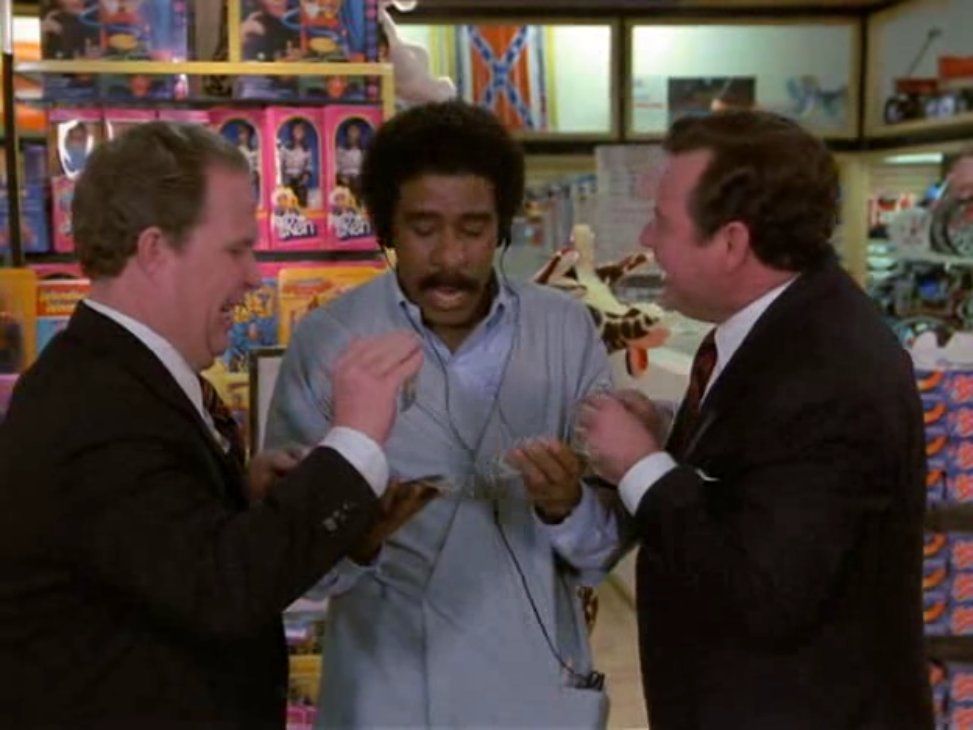 still from the film The Toy where Richard Pryor is being "bought" with a Confederate Flag image in the background