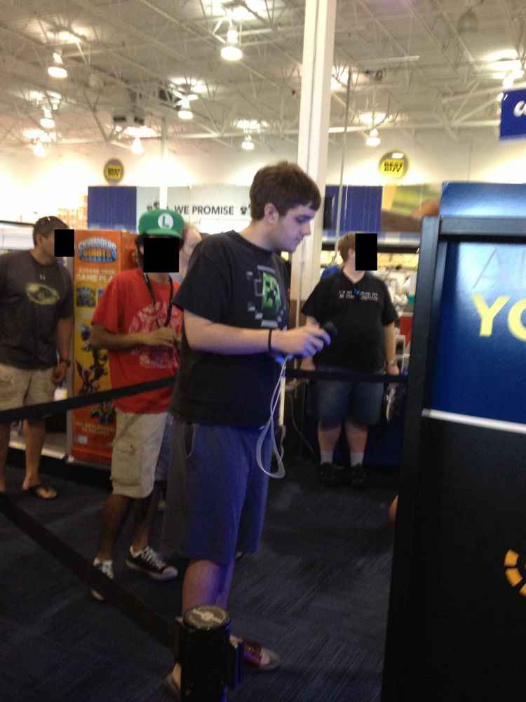 A lanky teenager holding a Wii Remote and Nunchuk in a Best Buy