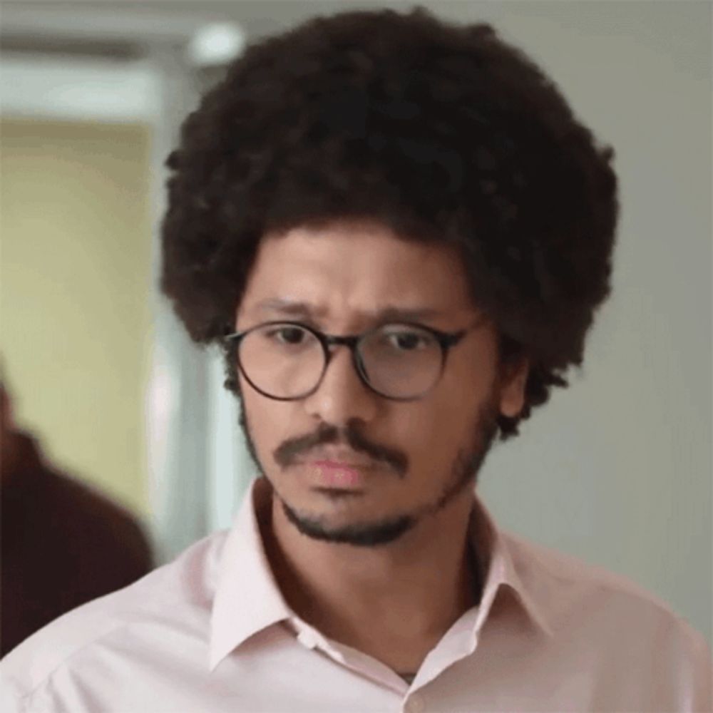 a man with an afro and glasses is making a silly face