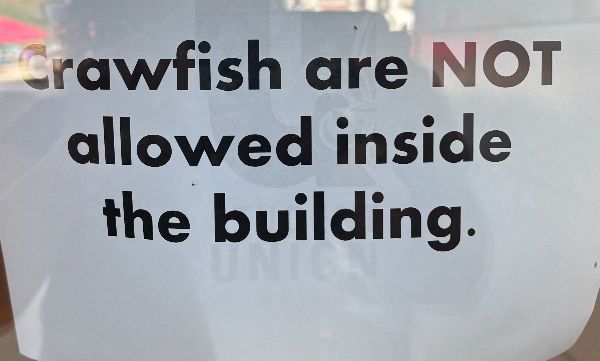 A sign on a university building limiting crawfish from receiving an education. “Crawfish are NOT allowed inside the building.”