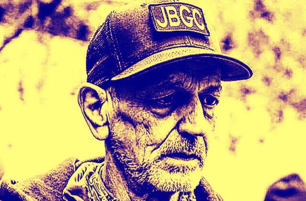 Sepia toned photo of Willem Van Spronsen wearing a hat with the text JBGC