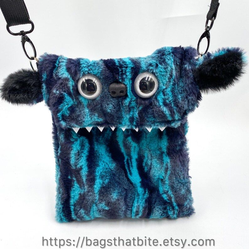 Teal and black soooft marbled faux fur crossbody bag with sparkly hand painted white eyes a soft Bear nose and cute ears. Small pointed foam teeth poke out of the fur. 