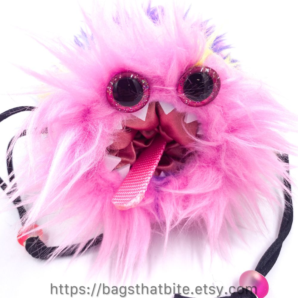 Pink on pink on pink with hand painted pink glitter eyes round drawstring bag with a ring of foam white teeth and a tongue you can pull to eject all the stuff you fed them. 