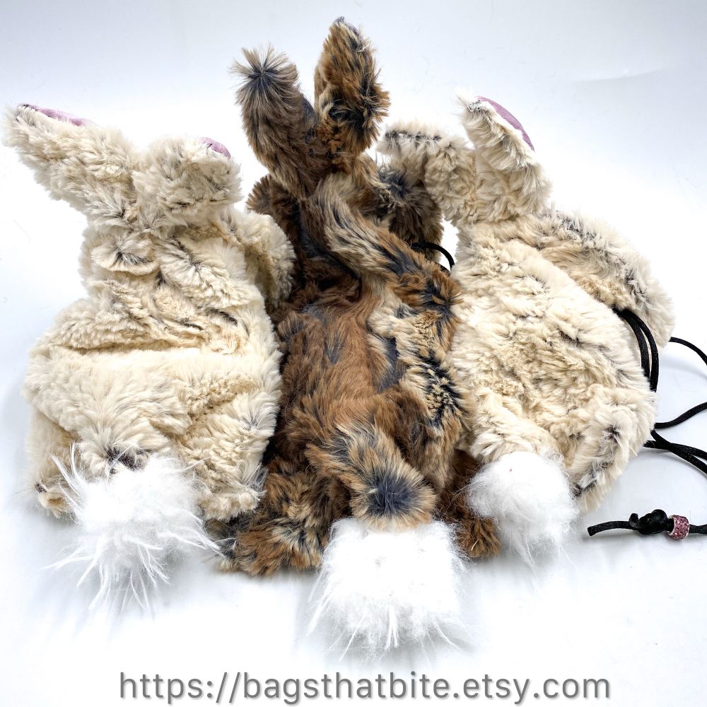 The back view of Bunny tails on 2 white and 1 brown bunny monster drawstring bag of devouring. 