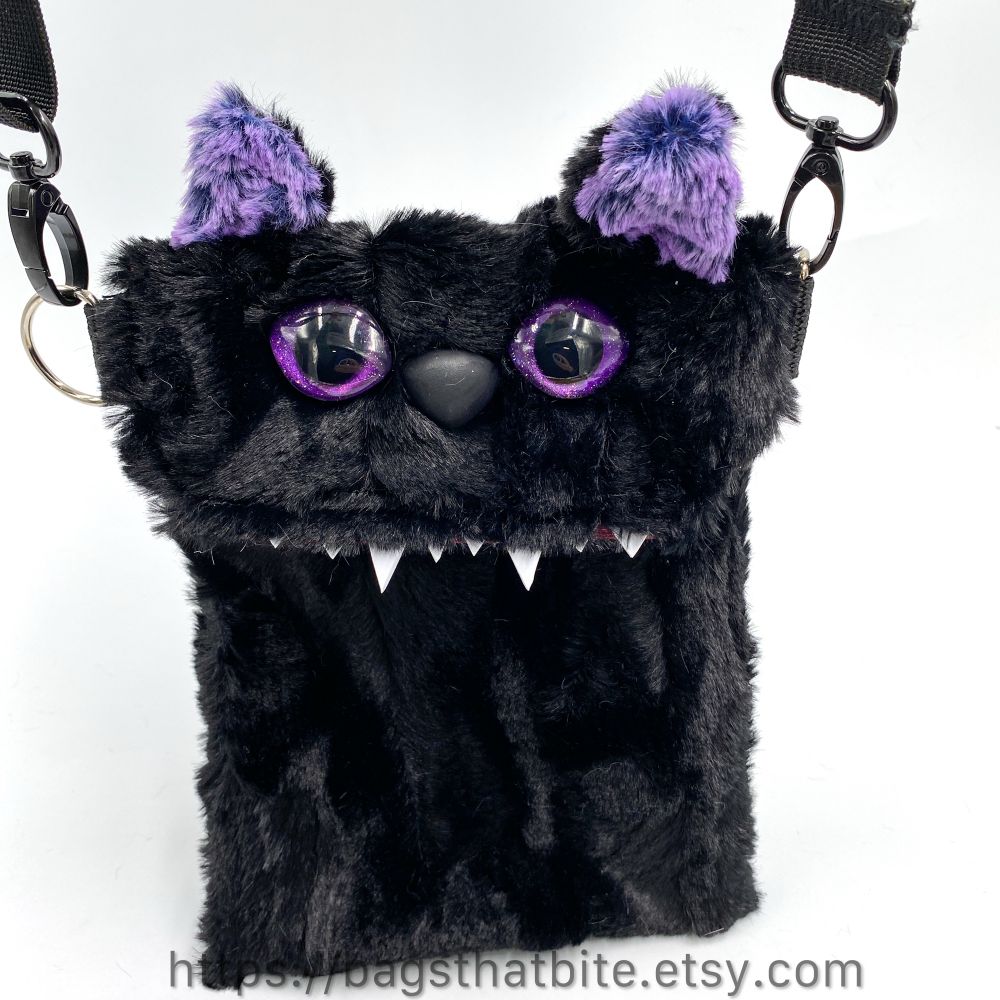 Close up of the purple ear monster hanging from the adjustable removable shoulder strap. 