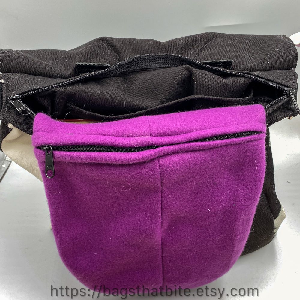 Inside look into the cow soft briefcase bag. A giant tongue zipper pocket in a pinky purple color is sticking out of the top zipper of the bag. The bag itself has a double pull zipper and the bag has an interior pocket. 