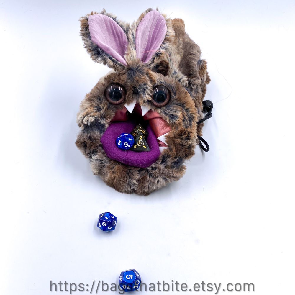 Bunny monster round mouth bag of devouring with dice food, purple tongue and pointed buck teeth and bunny ears and hand painted soulful brown eyes. 