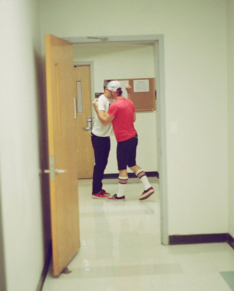 the picture taken frames Tyler and Josh in the middle of a doorframe, the angle and positions they're in makes it look as if they're kissing while they're going for a hug.