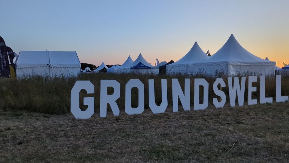 Groundswell sign with tents in background and sunsetting