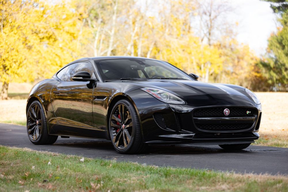 Der klassisch proportionierte Sportwagen in Black Ebony von halb vorne: alle Anbauteile in schwarz, großer Haifischgrill mit Gitterverkleidung und Querstrebe, scharf geschnittene Lufteinlässe daneben, längliche Scheinwerfer, konturierte Motorhaube, schwarz lackierte Doppelspeichenfelgen im Format zwanzig Zoll