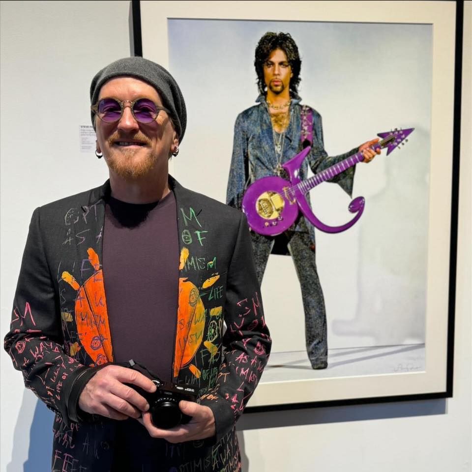 Photographer standing in front of a framed photo of Prince.