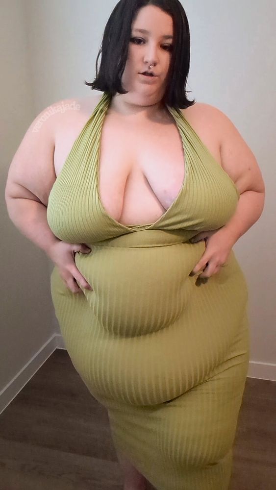 A photo of me, a very fat brunette, in a tight green halter dress that comes down below my knees. it shows off an abundance of cleavage. 