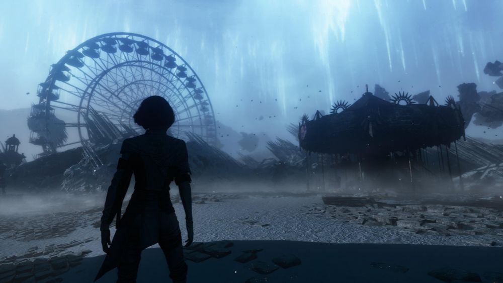 A screenshot from Clair Obscur: Expedition 33.
A broken down Ferris wheel sticks out of the sand to the left of the image and a highly decorated but rundown merry-go-round can be seen on the right. There is also a silhouette of a woman in the foreground on the left. 
