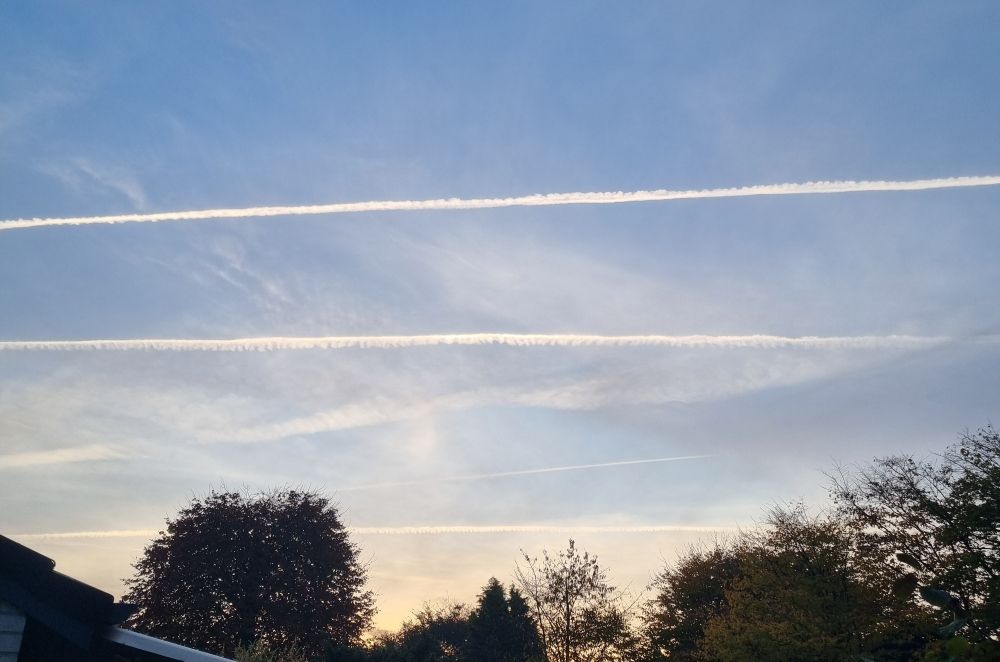 Blauer morgen Himmel. Man sieht drei sehr parallel verlaufende Kondensstreifen.