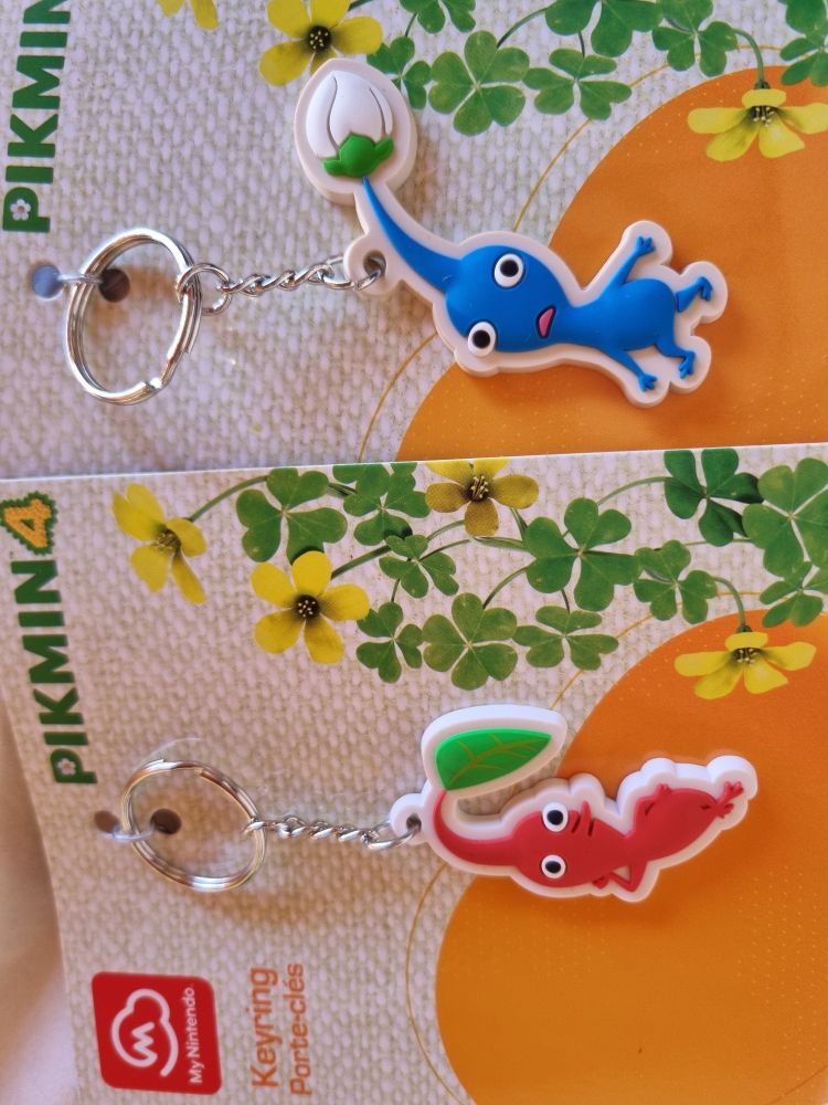 Zwei Schlüsselanhänger. Es sind Pikmin ein blaues und ein rotes.