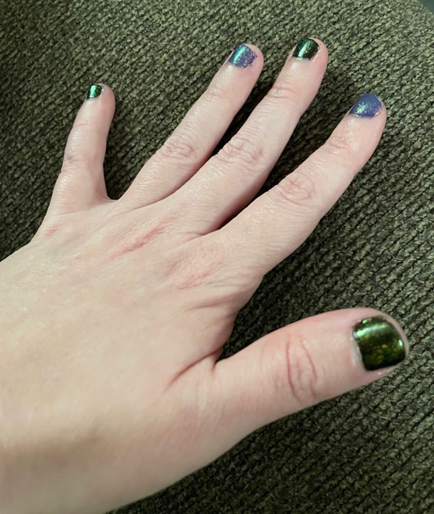 A left hand with painted fingernails, black & purple, all with a sparkly coat