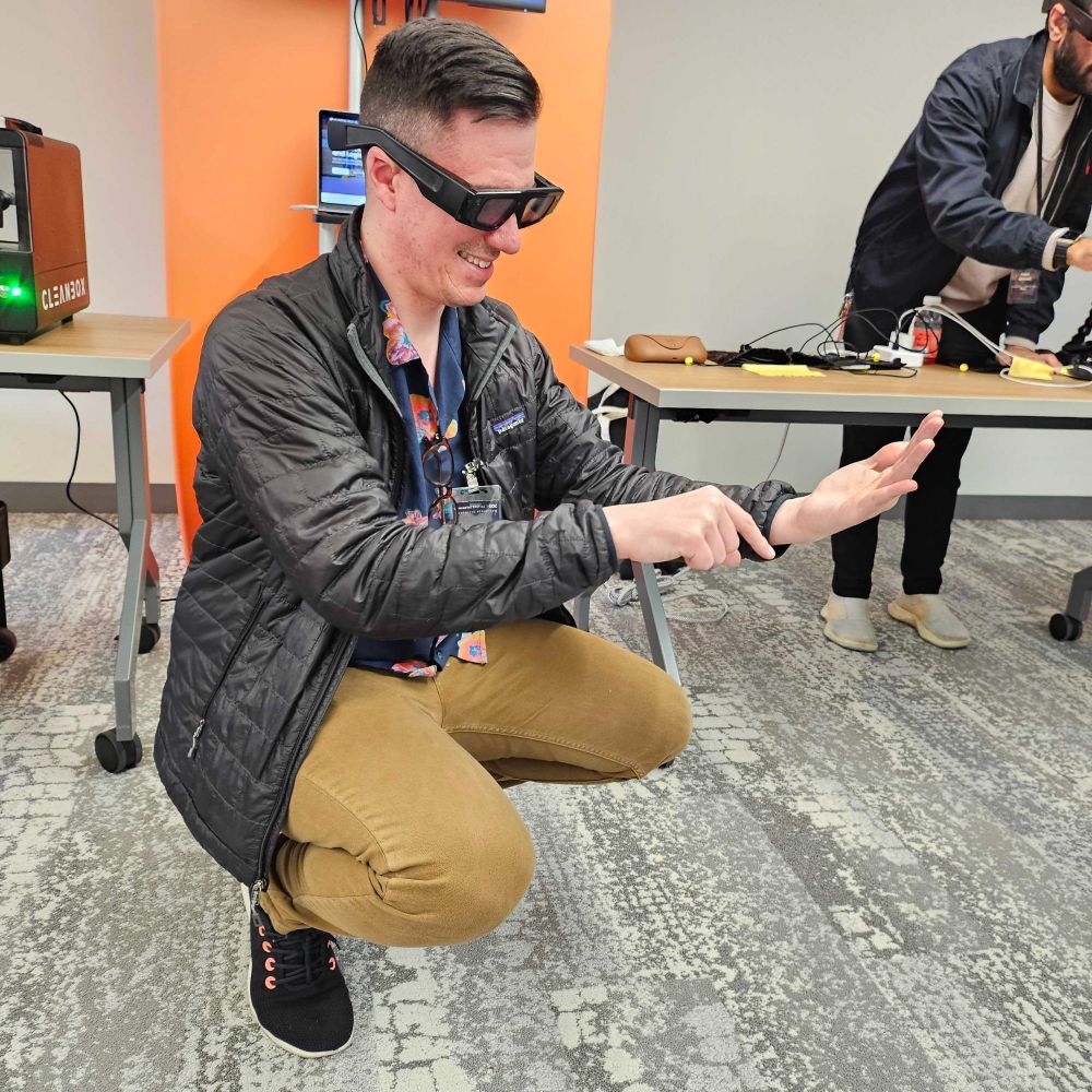 Ryan, hunches over wearing XR glasses and attempts to pet an unseen object.