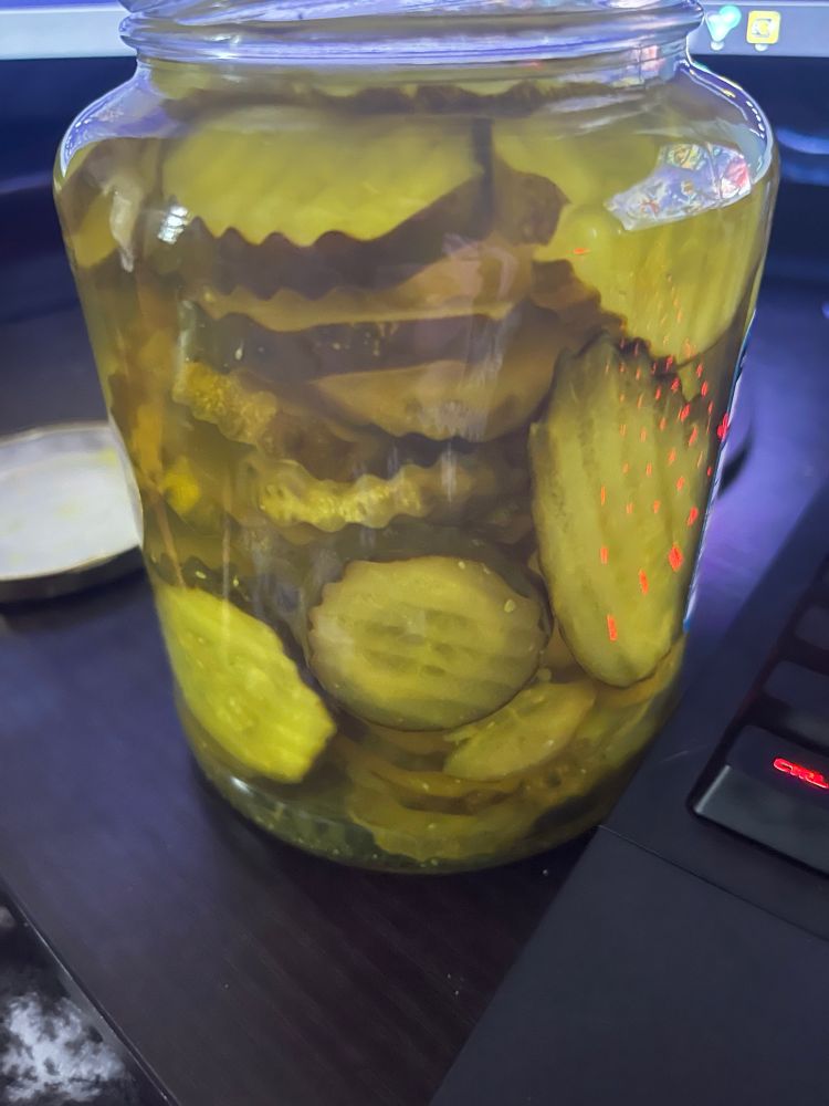 A glass jar of sliced dill pickles 