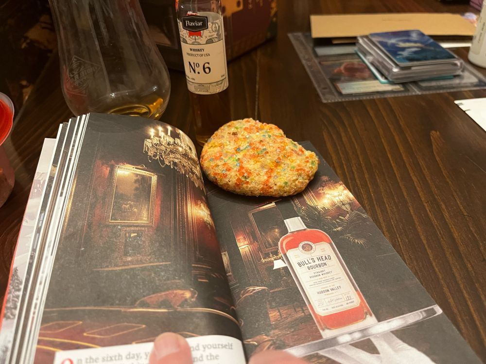Whiskey vial #6, half eatena christmas cookie with red and green sprinkles and a picture from the flaviar journal of the Bull's Head Bourbon bottle  