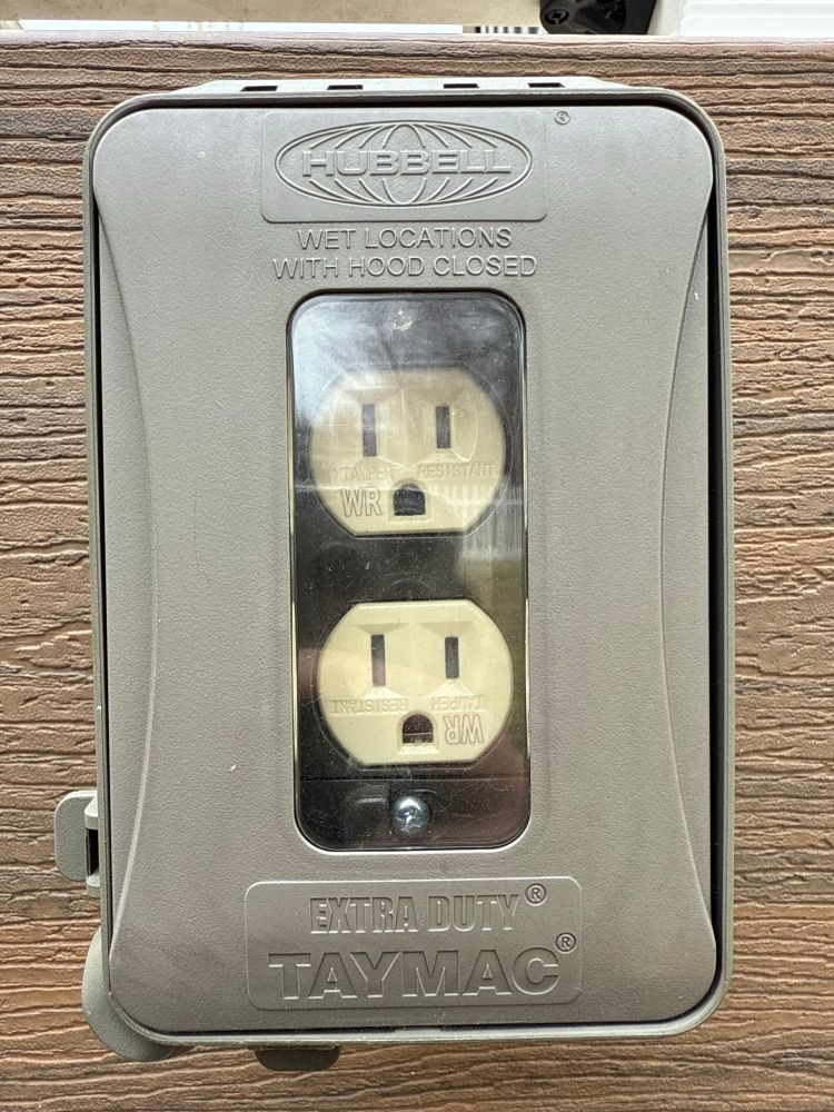 An outdoor electrical outlet, with a cover by Hubbell, whose logo is nearly exactly like the fictional company Lumon’s