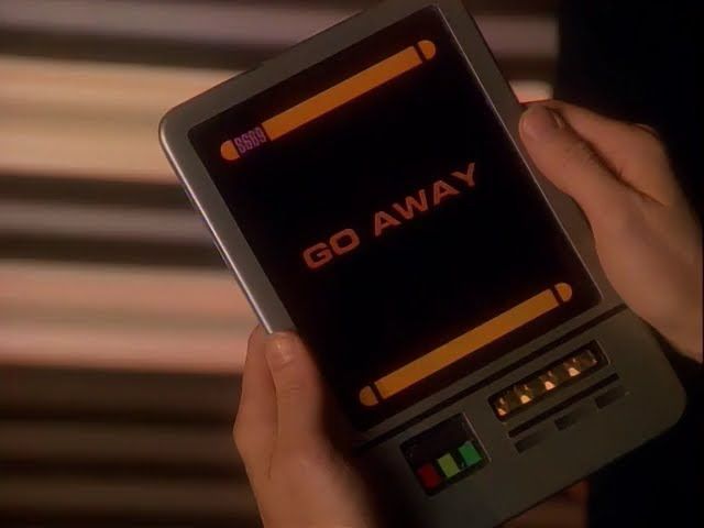 a closeup of jadzia’s hands holding a PADD julian handed her that reads “GO AWAY”