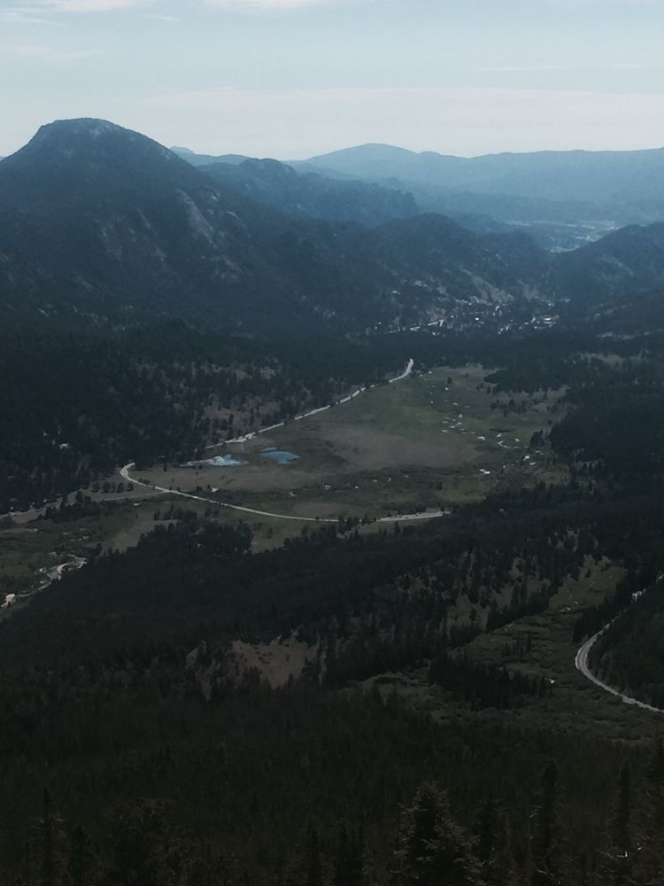 A photo of Rocky Mountain national park from a lookout down into a valley with Mountains around it. 