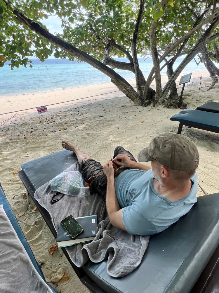 Maken stickar i solstolen, havet bakom