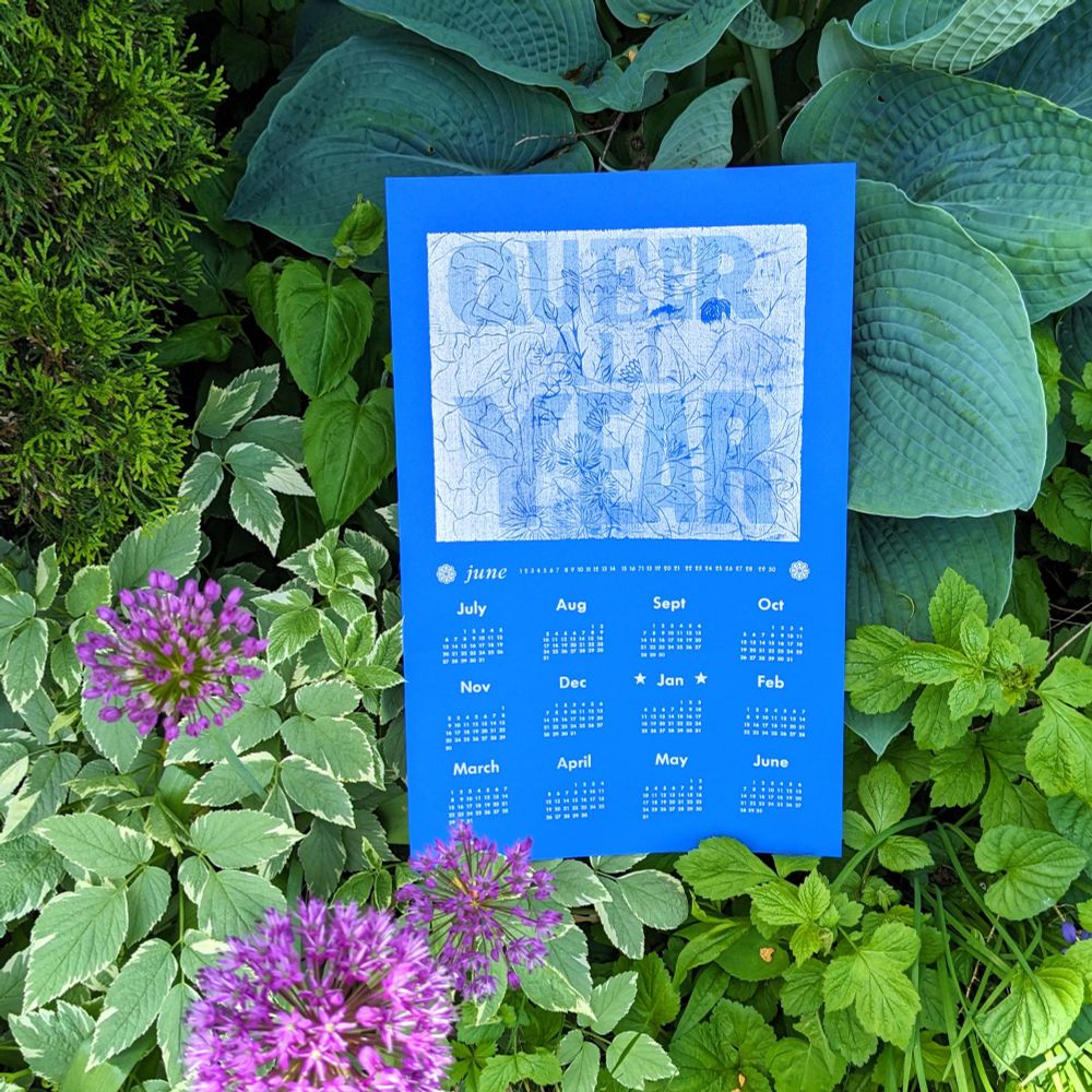 An 11" x 17" print on bright blue card stock, letterpress and wood block, metallic silver ink with transparent cyan letterpress reading "QUEER ALL YEAR" overlaid over a silvery garden scene depicting four ethereal nude figures of varying genders among blooming flowers from every season: peonies, carnations, asters and lilacs. This image is above silver letterpress months, June 2025 through June 2026.