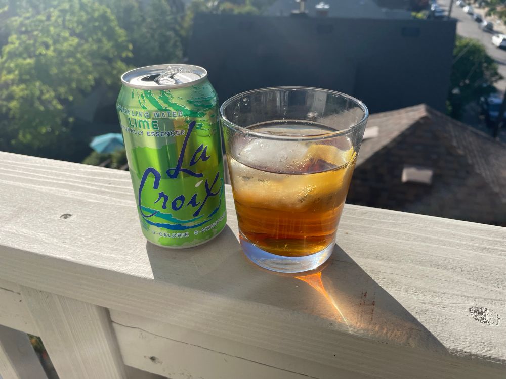 Photo of a La Croix can next to a glass with soda water, ice cube, and a splash of barrel aged sherry.