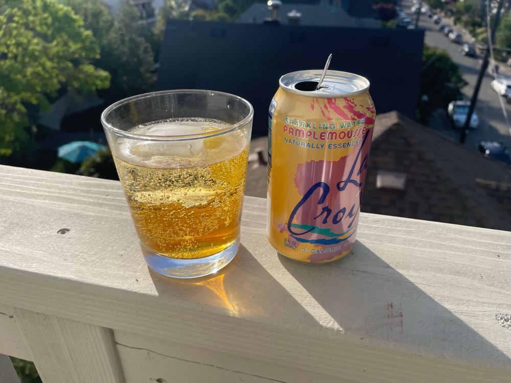 Photo of glass with faux americano next to a emptying can of lacroix