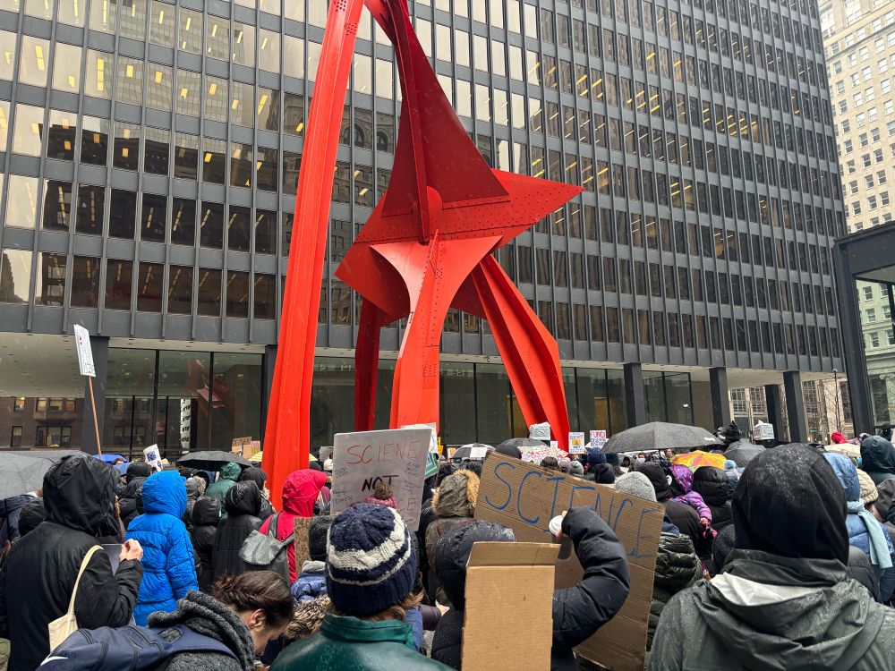 Flamingo, an orange sculpture by American artist Alexander Calder is shown surrounded by protesters.