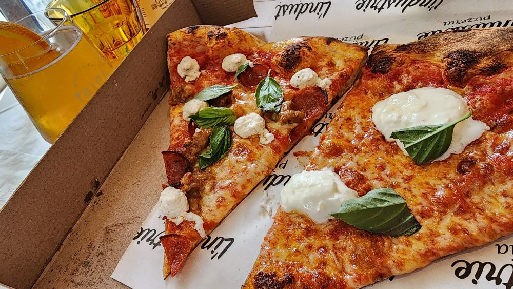 Two NY style pizza slices topped with basil and big globs of extra cheese. 