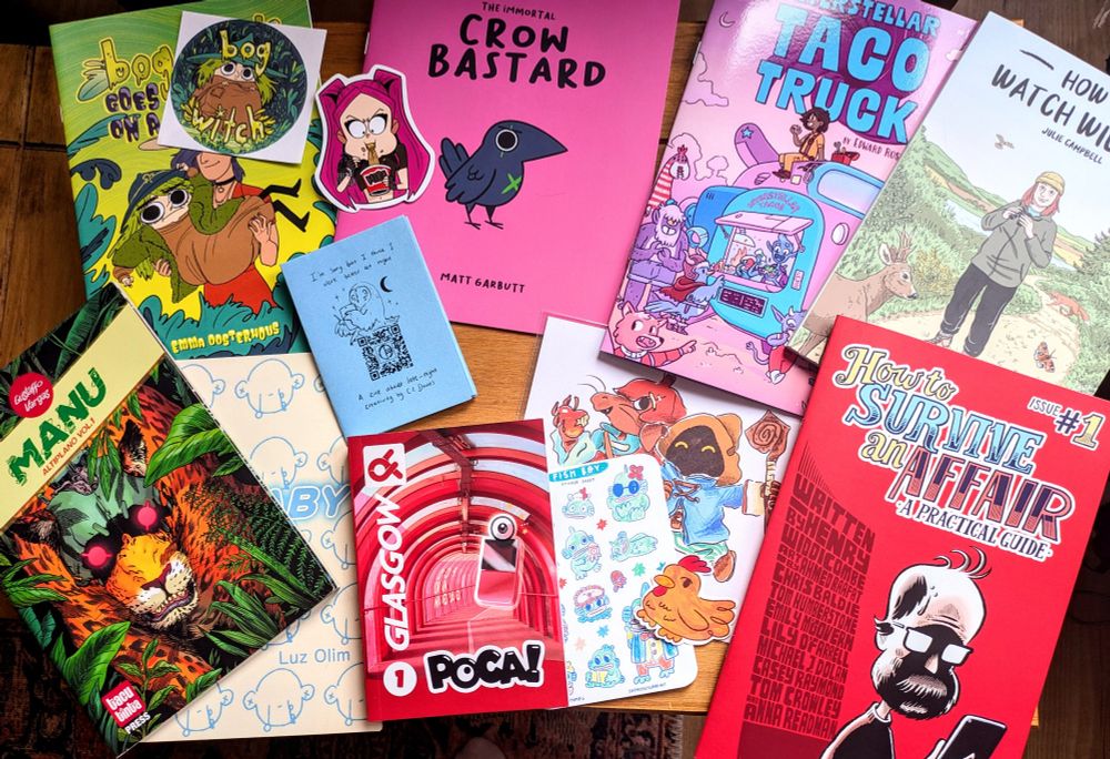 A collection of colourful zines, prints and stickers by various artists that attended Sequential Scotland, laid out on a table