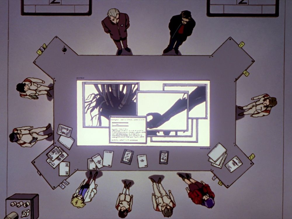 Fuyutsuki, Gendo, Aoba, Misato, Hyuga, Maya, Ritsuko, and other NERV personnel standing around a table