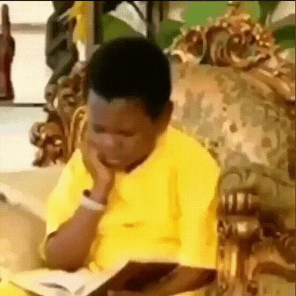 a young boy in a yellow shirt is sitting on a couch reading a book