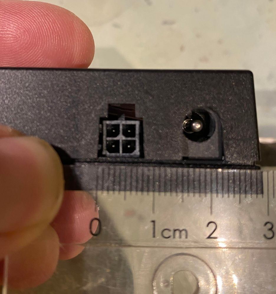 A sideview of a Märklin 24089 with two connectors, a round barrel power supply on the right, and a mystery square connector on the left. A ruler below shows the connector to ≈ 6mm wide. 