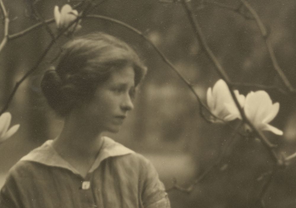 Close-up of Millay's face in the portrait, surrounded by large white flowers. She gazes off camera with a soft, unsmiling expression. 