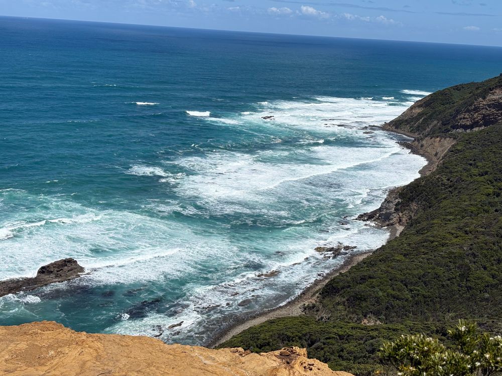 A beautiful shoreline with teal blue water crashing against mountains 