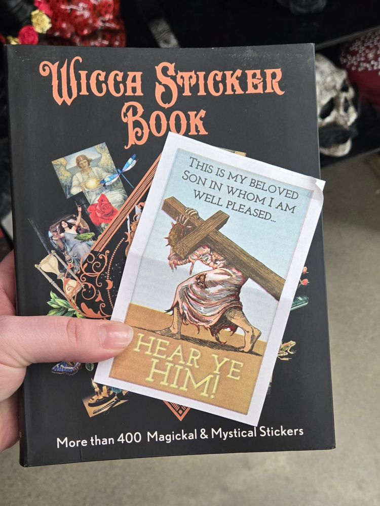 A picture of a book labeled "Wicca Sticker Book" with a small pamphlet featuring a bloody jesus carrying a cross