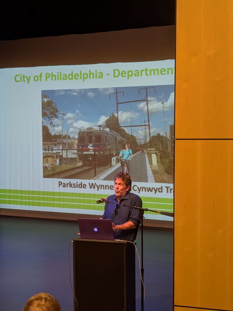 Chris Leswig (Lower Merino Twp Planning Director) at the NW Schuylkill Trails Summit 2025, with photo of new planned infrastructure behind.