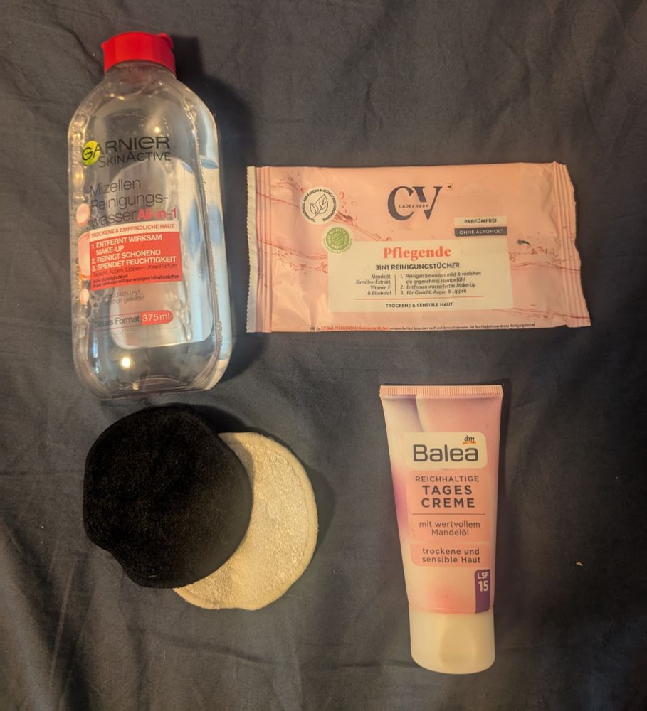 Mehrere Badeprodukte.

Oben Links: eine durchsichtige Flasche Mizellen Reinigungswasser von Garnier

Oben rechte: eine fast leere Packung Pflegende Gesichtsreinigungstücher von CV

Unten links: ein weißes und ein schwarzes Wattepad

Unten rechts: eine kleine Tube reichhaltige Tagescreme von Balea