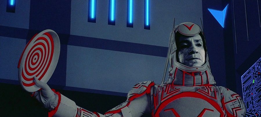 Sark from Tron sternly addresses his captive programs. He is holding a Disk.