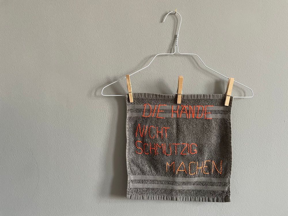 farbig gestickt auf einem grauen Handtuch