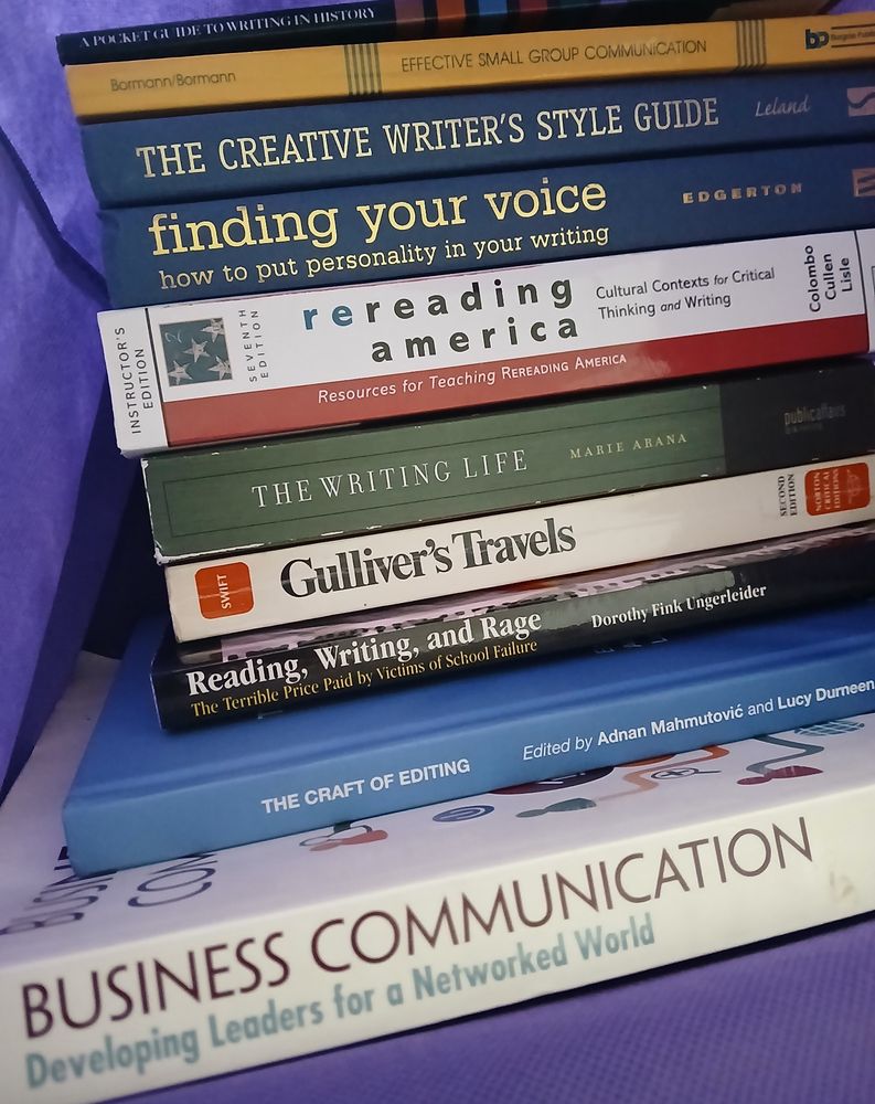 A stack of 10 books in a reusable purple tote.

From top to bottom:

A Pocket Guide to Writing in History, 2nd Edition by Mary Lynn Rampolla

Effective Small Group Communication, 4th Edition by Ernest G. Bormann and Nancy C. Bormann

The Creative Writer's Style Guide by Christopher T. Leland

Finding Your Voice: How to Put Personality in Your Writing by Les Edgerton

Rereading America: Cultural Contexts for Critical Thinking and Writing by Gary Colombo, Robert Cullen, and Bonnie Lisle

The Writing Life: Writers on How They Think and Work, a collection from the Washington Post Book World, edited with an introduction and commentary by Marie Arana

Gulliver's Travels by Jonathan Swift

Reading, Writing, and Rage by Dorothy Fink Ungerleider, M.A.*

The Craft of Editing by Routledge, edited by Adnan Mahmutović and Lucy Durneen

Business Communication: Developing Leaders for a Networked World by Peter W. Cardon