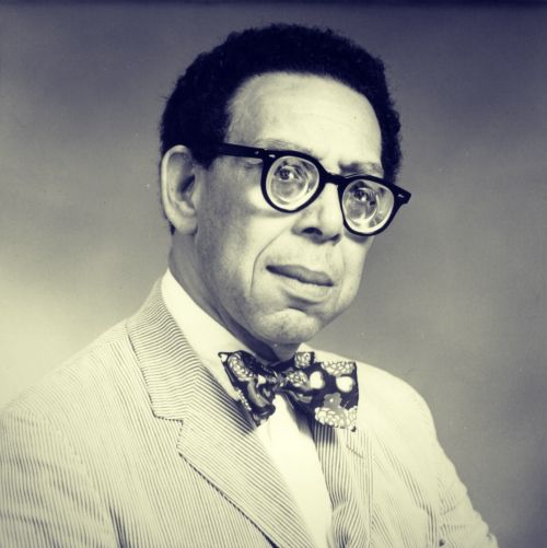 A b/w photo portrait of Robert Hayden.
He is wearing his thick eyeglasses, a suit, and bowtie.
Photo credit: unknown