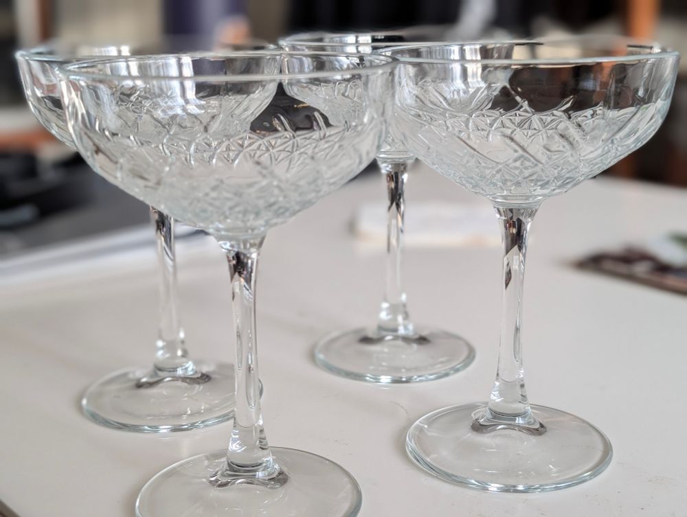 A set of four coupe glasses with an intricate design