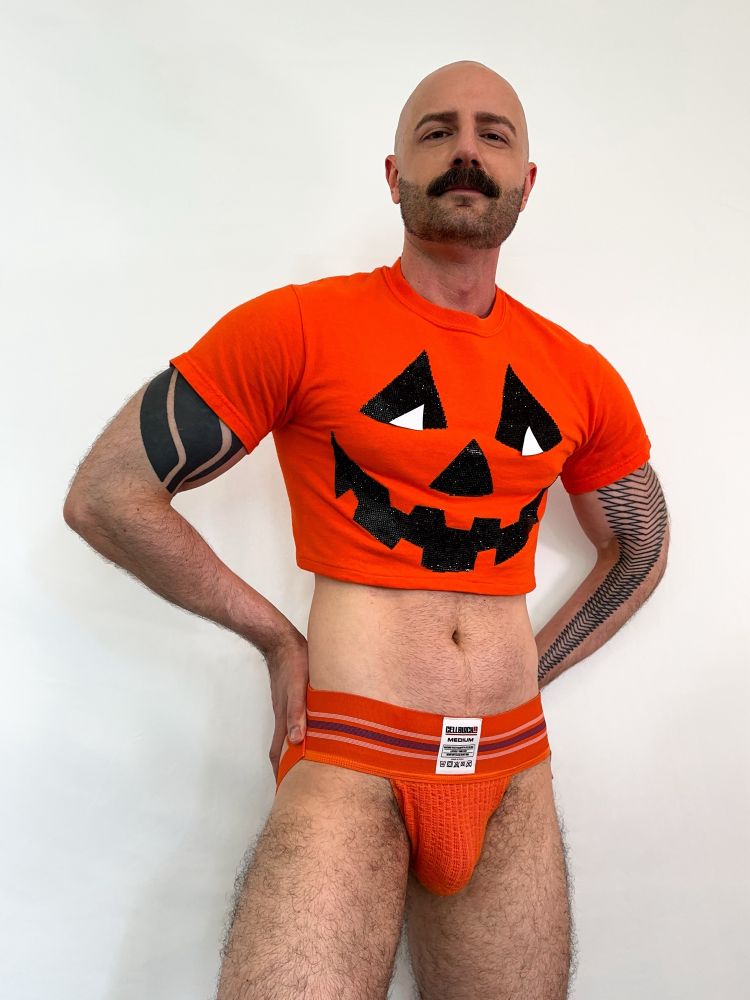 Me wearing a jack-o-lantern crop top and an orange Cellblock13 jockstrap. 