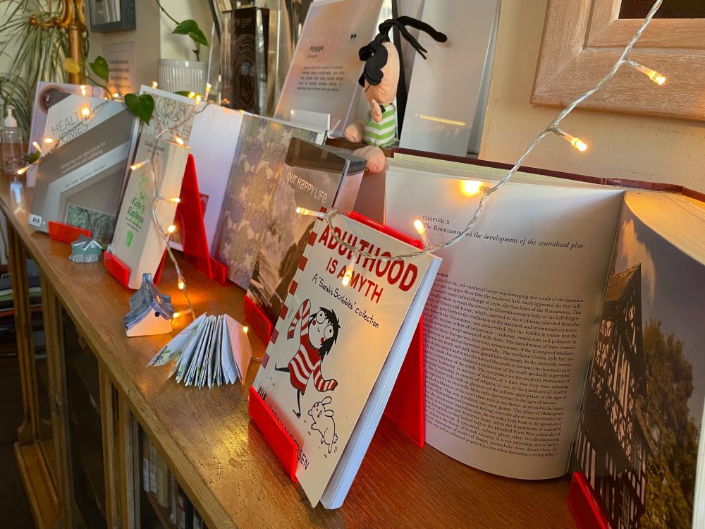 A photo close up of one of the Hugge library display books - "Adultgood is a myth", with paper houses in the background.