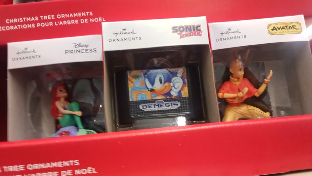 A holiday ornament of a Sonic Sega Genesis cartridge, flanked by Aang and Ariel