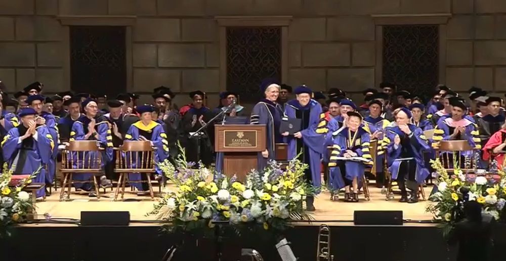 Stage with people in caps and gowns, with Dr. Shrager at center receiving the award